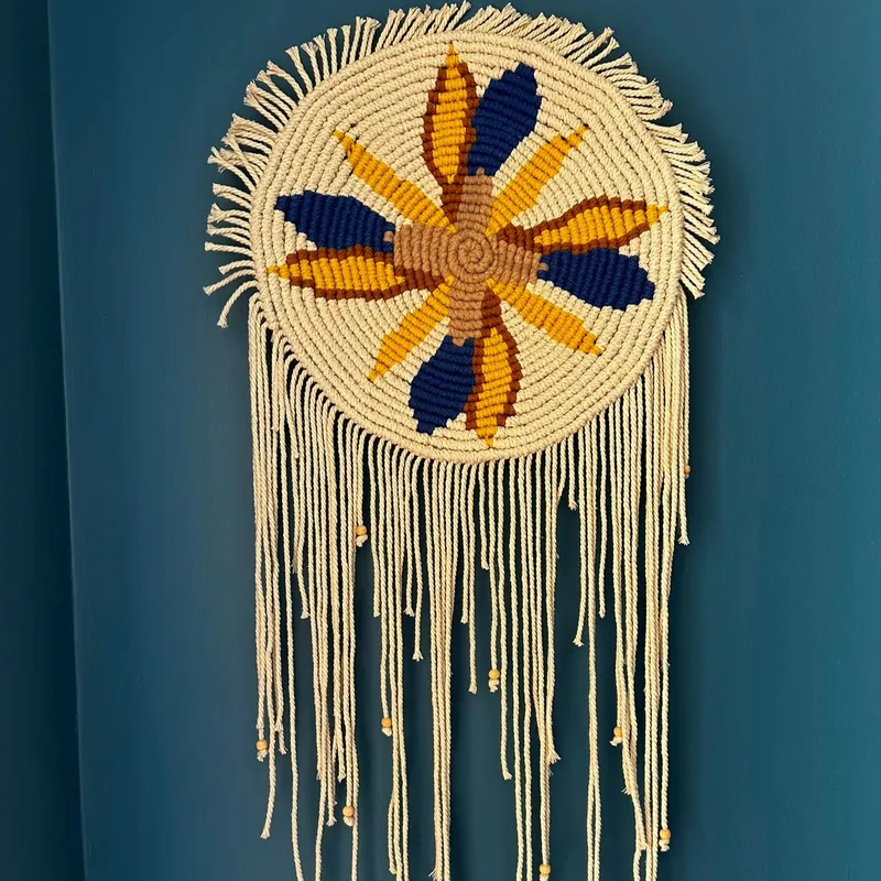 Création MAM'CRAM : attrape-rêves en macramé à motif de fleur bleue et jaune, sur fond bleu canard.
