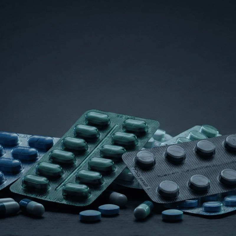 Plaquettes de comprimés et gélules sur fond sombre, visuel d'accueil de l'application SafePills.